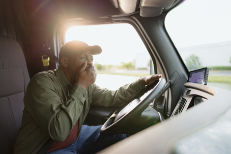 Tired truck driver yawning while driving on the highway
